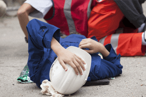 A victim of a labor law and construction accident lies on the ground after being injured