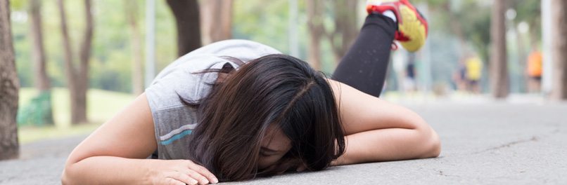 A woman lies facedown after a slip and fall accident on a paved walkway