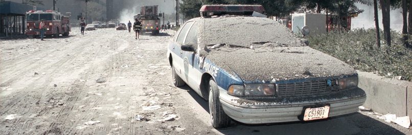 Toxic dust coats the landscape around ground zero, including a police car and the street
