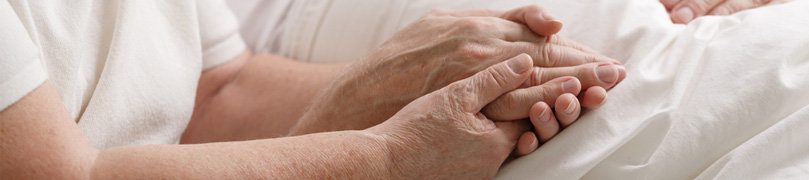 An elderly couple holds hands as they cope with Uloric side effects